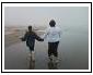 photo of girl and lady walking on a beach facing away